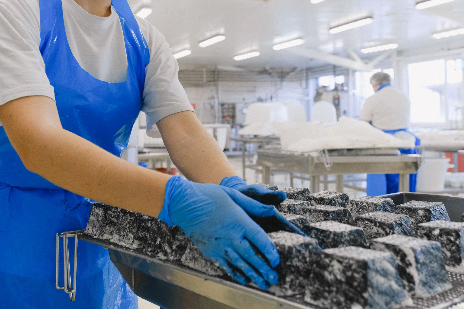 Food production workers in protective clothing handling product on a line
